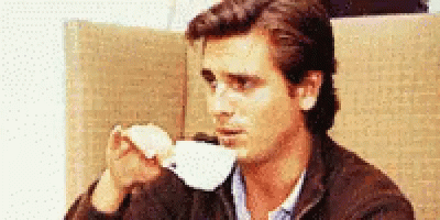 A man takes a sip of tea from a white teacup, making sure to lift his pinky as he does so
